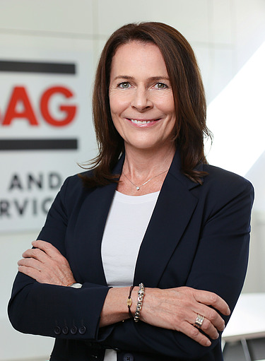 Foto von einer Frau im Businesslook vor einer Wand, auf der STRABAG Property and Facility Services steht