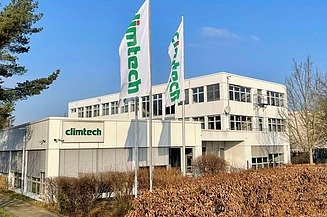 Ein kleines Gebäude mit der Aufschrift Climtech und 2 Flaggen davor