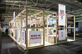 Messestand EXPO REAL Bild eines zweistöckigen Messestandes aus Holz mit Bannern und Pflanzen bestückt