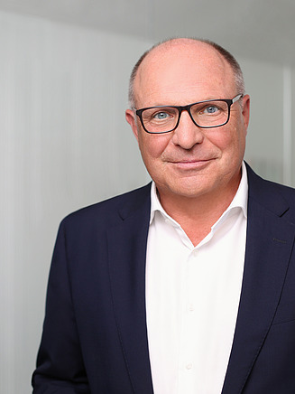 Foto von einem Mann in Anzug vor einer Glasscheibe