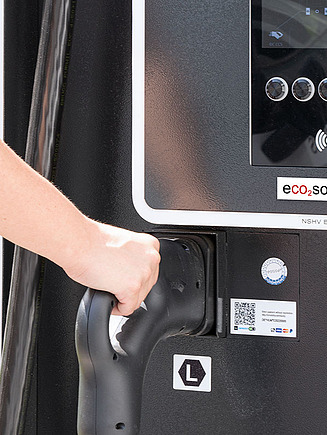 Nahaufnahme einer Hand an einer eco2mobility E-Zapfsäule mit eco2solutions Aufkleber