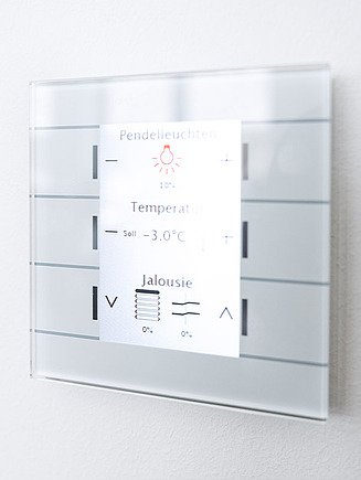 Bild von einer Steuereinheit mit Möglichkeit zur Steuerung von Licht, Temperatur und Jalousie, die an einer Wand hängt.