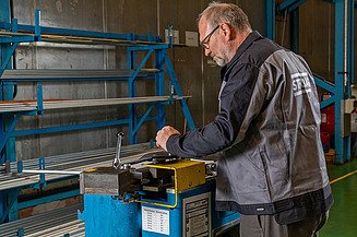 Produktionsservices Foto von einem Mann in Arbeitskleidung, der an einer Maschine arbeitet