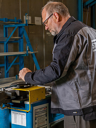 STRABAG Mechanical Engineering Produktionsservices Foto von einem Mann in Arbeitskleidung, der an einer Maschine arbeitet