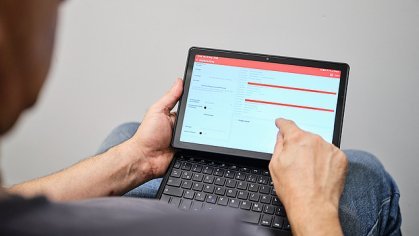 Fotografie zaměstnance, který pracuje s tabletem, přes rameno