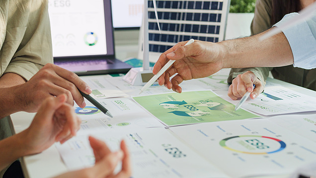Picture of several hands pointing at work material with pens