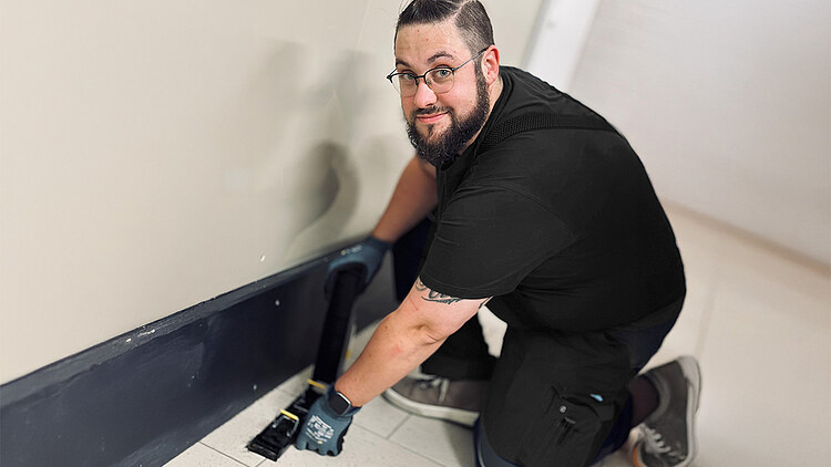 Obrázek klečícího kontrolora škůdců, který drží zařízení na zemi