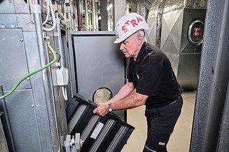 Höchstverfügbarkeit Foto von einem Mitarbeiter mit Helm, der den Filter einer Lüftungsanlage tauscht