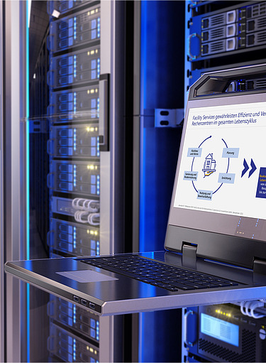A server room with several server cabinets illuminated with blue lights. In the foreground is a retractable laptop tray with a laptop displaying a presentation on facility services and data centers. 