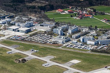 Luftaufnahme einer großen Anlage mit vielen Gebäuden und Landebahn