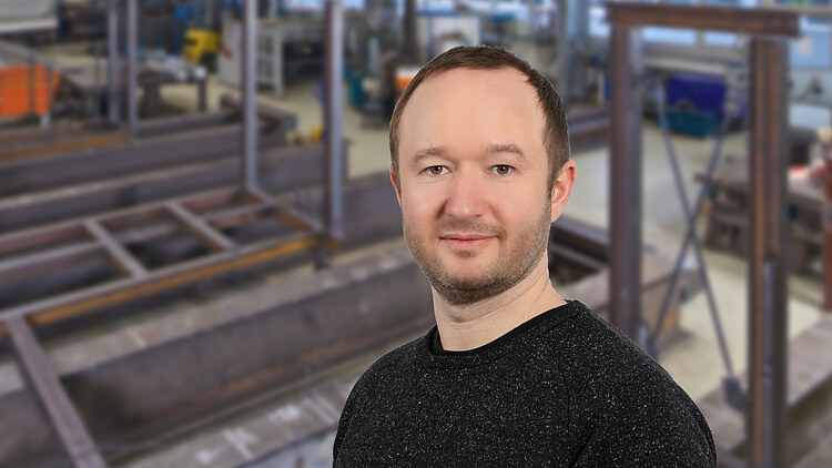 Obrázek muže stojícího před ocelovou konstrukcí