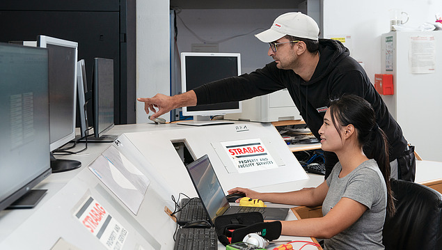 Fault management Photo of two employees at a table with monitors and a laptop top