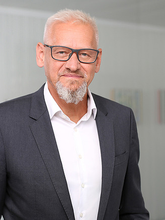 Foto von einem Mann in Anzug vor einer Glasscheibe