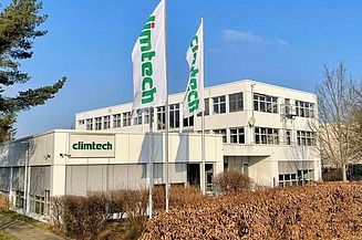 Photo of a small building with the letters climtech and two flags in front of the building