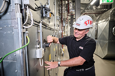 Ein Techniker mit Schutzhelm führt Wartungsarbeiten an einer großen industriellen Anlage durch.