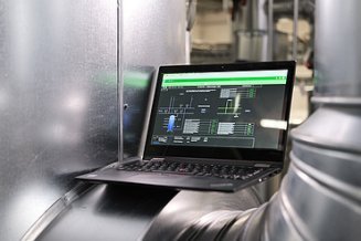 Photo of a laptop showing an application and located between silver pipes