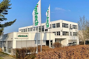 Ein kleines Gebäude mit der Aufschrift Climtech und 2 Flaggen davor
