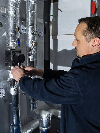 Foto von einer Person, die an einem Rohr im Keller arbeitet