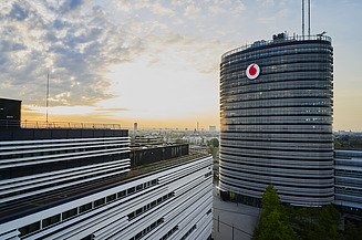 Vodafone Campus in Düsseldorf Photo of a building with Vodafone logo, in front of a sunset with clouds