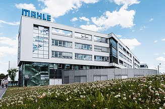 STRABAG PFS MAHLE Foto von einem weißen Gebäude mit zahlreichen Fenstern und dem Firmennamen MAHLE auf dem Dach