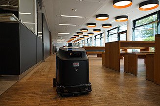 Foto von einem Reinigungsroboter in einem großem Raum mit Tischen