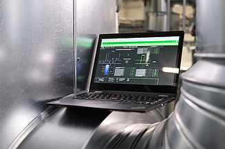 Photo of a laptop showing an application and located between silver pipes