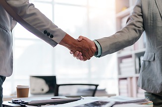 Fotografie dvou rukou tisknoucích se nad stolem