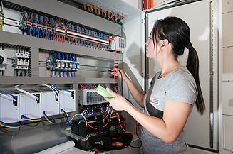 Energiemanagement Foto von einer Mitarbeiterin, die Messungen an einem Schaltschrank durchführt