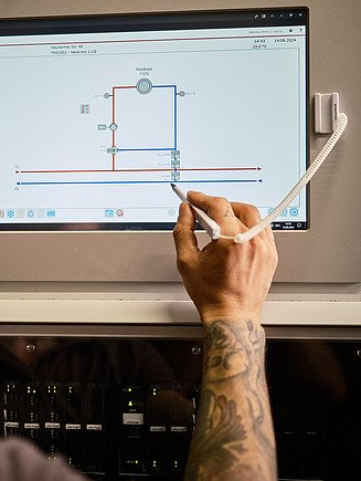 Foto von einer Person von hinten, die mit einem Stift ein Tablet und eine Anwendung bedient