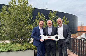 Schlüsselübergabe Instalace Praha Foto drei Männern auf einem Balkon, die einen großen Schlüssel halten