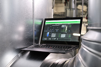 Photo of a laptop showing an application and located between silver pipes