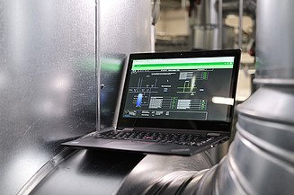 Photo of a laptop showing an application and located between silver pipes