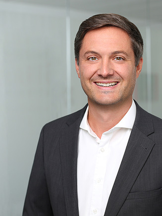 Foto von einem Mann in Anzug vor einer Glasscheibe