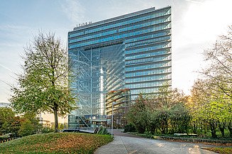 Stadttor Düsseldorf Foto von einem gläsernen Gebäude, das ein Tor bildet, davor sind Bäume