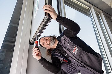 Obrázek správce opravujícího okno zespodu