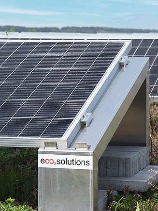 Bild von einer Photovoltaik-Anlage auf einem begrünten Dach und mit eco2solutions Aufkleber