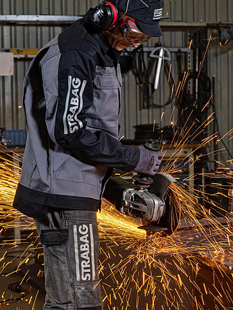 STRABAG Mechanical Engineering Stahlbau Bild von einer Person, die mit einem Winkelschleifer Stahl schneidet