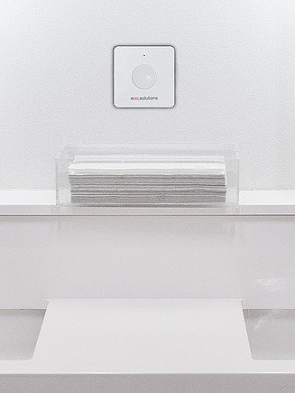 Picture of a double washbasin, in the middle hangs a white box with a button on the wall