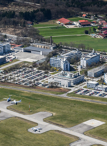 Luftaufnahme einer großen Anlage mit vielen Gebäuden und Landebahn
