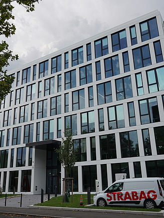 Modernes Bürogebäude mit STRABAG-Firmenwagen im Vordergrund