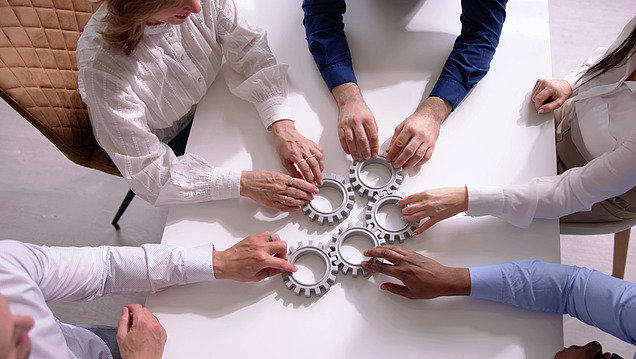 Image of a group of people holding gears together on a table