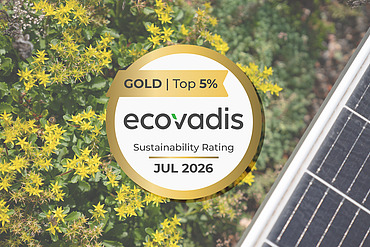Foto von einer PV-Anlage neben gelben Blumen und dem EcoVadis Gold Siegel im Vordergrund
