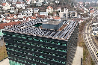 Luftaufnahme eines hohen Gebäudes, auf dem das Dach komplett mit PV-Anlagen versehen ist