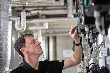 Ein Techniker überprüft und bedient eine Schalttafel in einem industriellen Umfeld