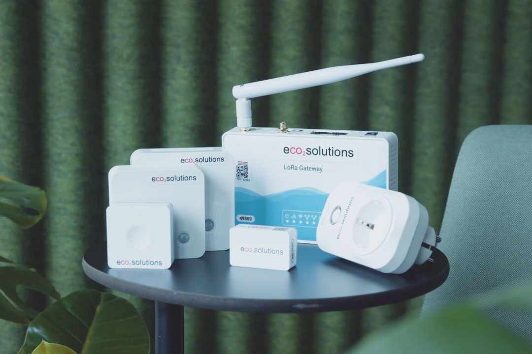 Bild von verschiedenen Arten von eco2state Sensoren, welche auf einem runden Tisch vor grünem Hintergrund stehen.  