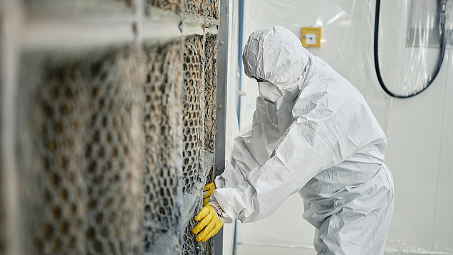 Bild einer Person im Schutzanzug, die ein Teil einer Luftanlage bearbeitet