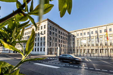 Bild von einem historischen Gebäude, die Vorfahrt ist beflaggt, auf der Straße ist ein vorbeifahrendes Auto zu sehen