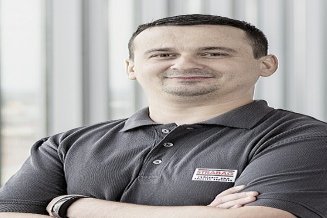 STRABAG PFS Mitarbeiter steht mit verschränkten Armen vor einer modernen Fensterfront