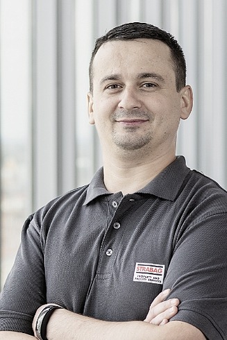 STRABAG PFS Mitarbeiter steht mit verschränkten Armen vor einer modernen Fensterfront