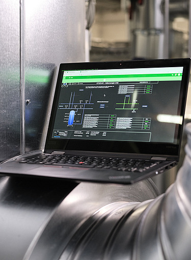 Photo of a laptop showing an application and located between silver pipes